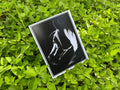 A square art print featuring a black and white sketch of a horse's head, placed on a bed of green leaves.
