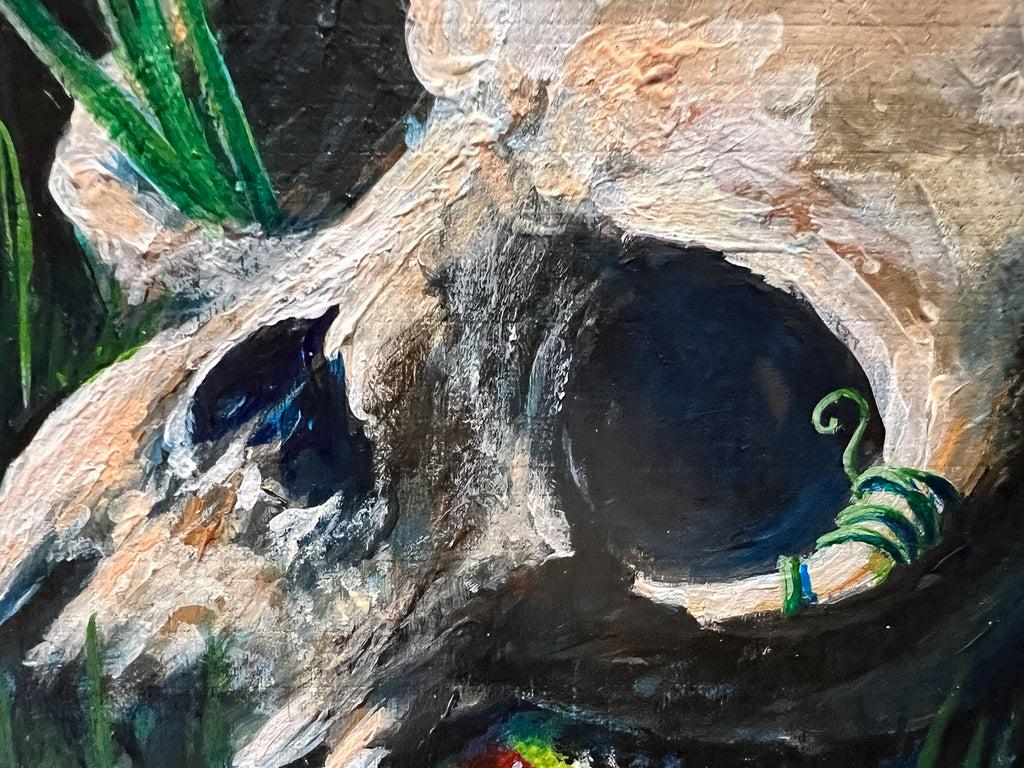 Close-up of a textured painting depicting a skull with green leaves and a curled vine in dark recesses.