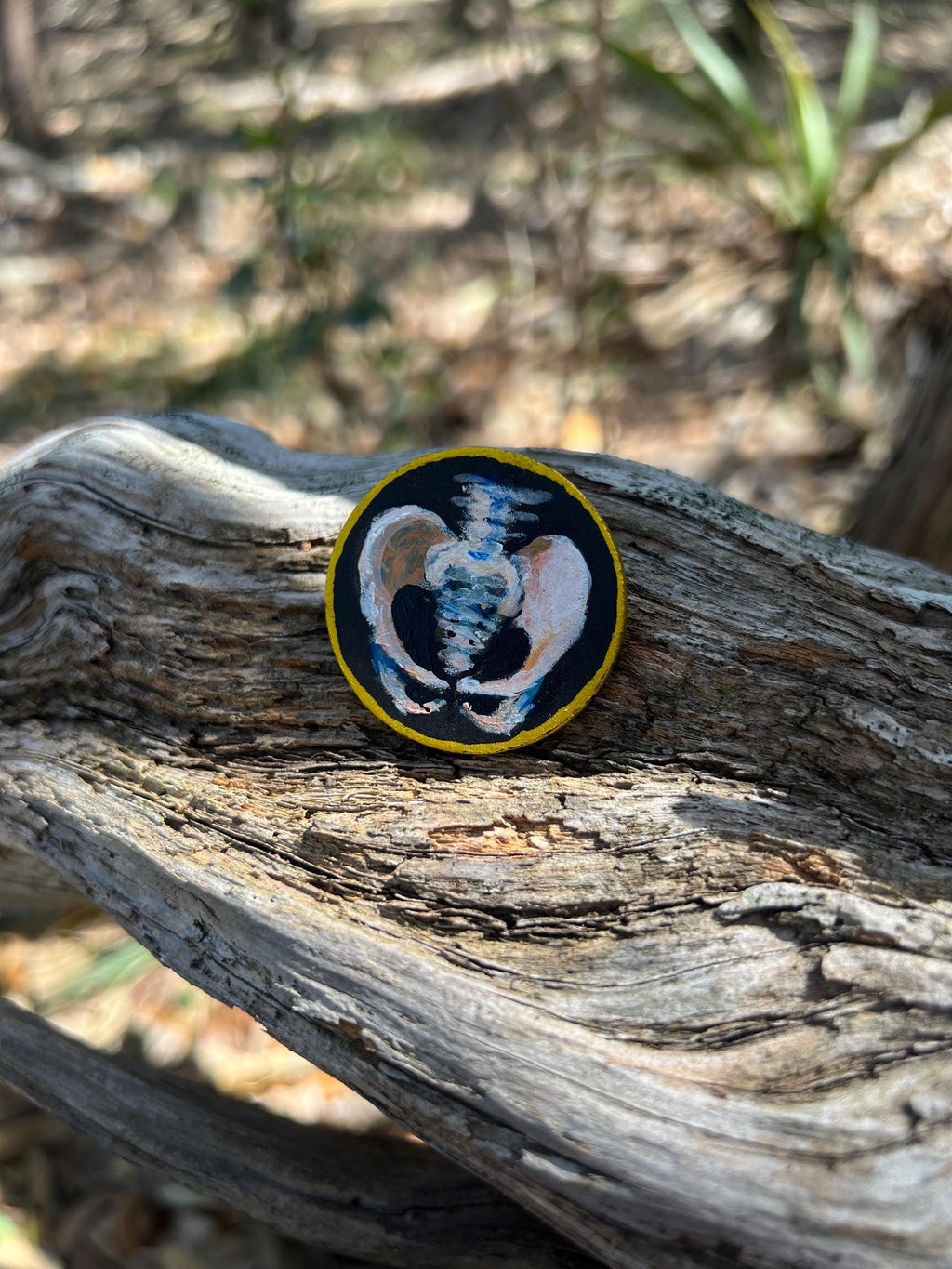 Handpainted Wooden Coin Token with a skull on the heads side and hip bones on the tails side.